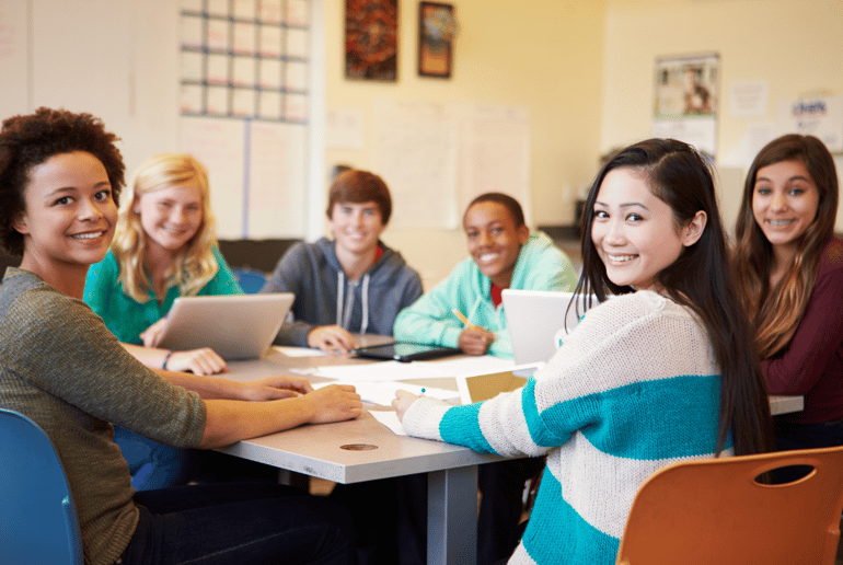 A group of teenage students sitting at a table doing homework