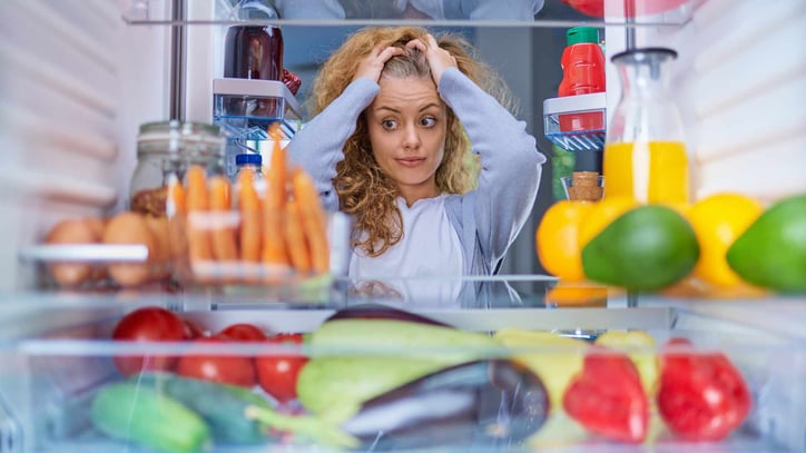 Teenage girl looking in fridge with frustration