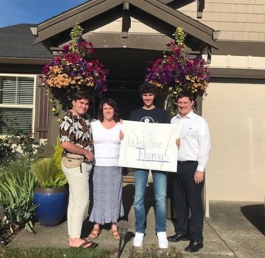 family and student in front of home with welcome sign