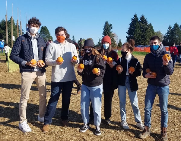 teens holding mini-pumpkins at a pumpkin patch