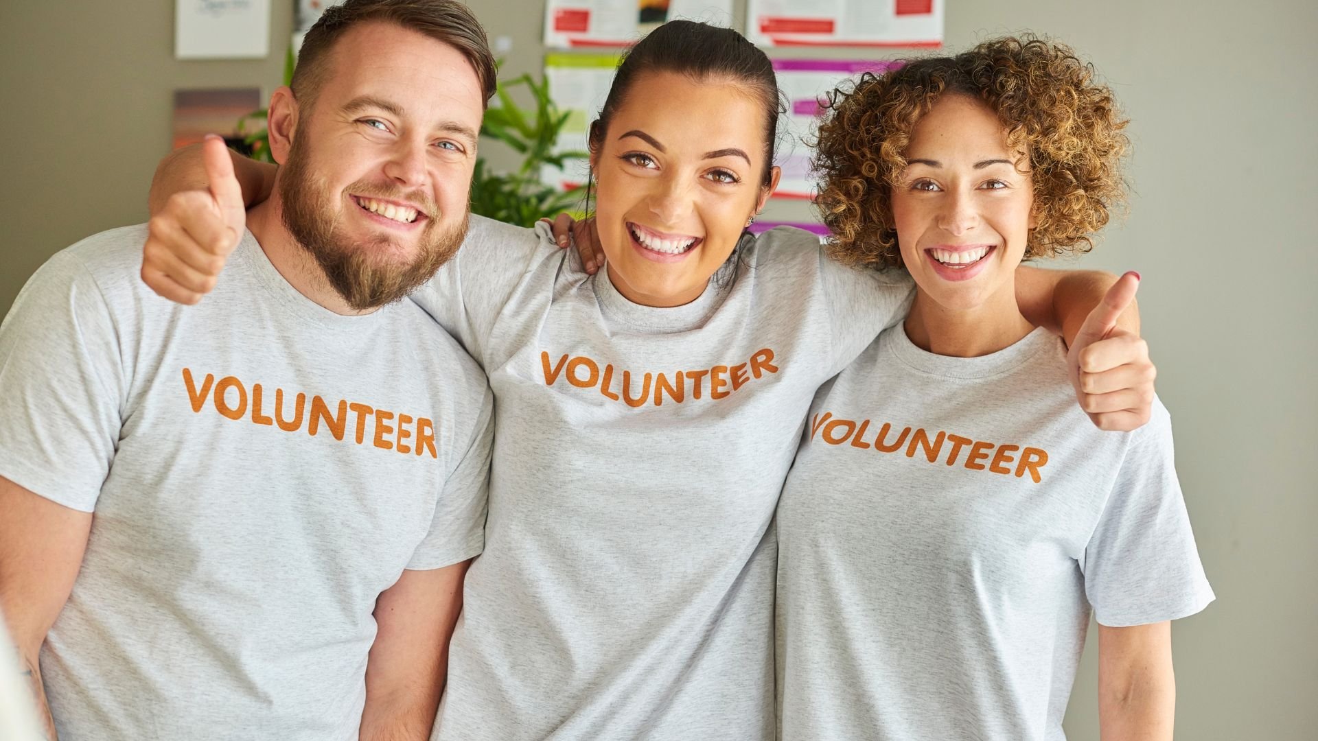 Three smiling people wearing volunteer t-shirts