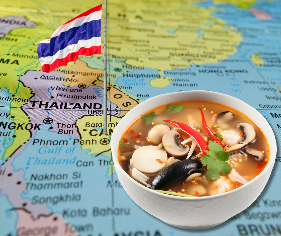 Tom Yum dish in front of the Thai map and flag.