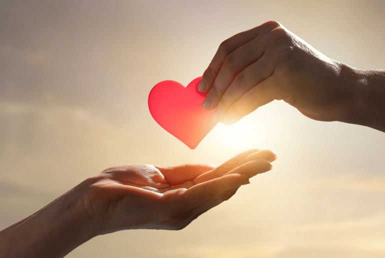 One hand placing a heart in another