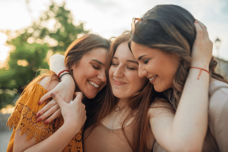 three friends smiling and hugging