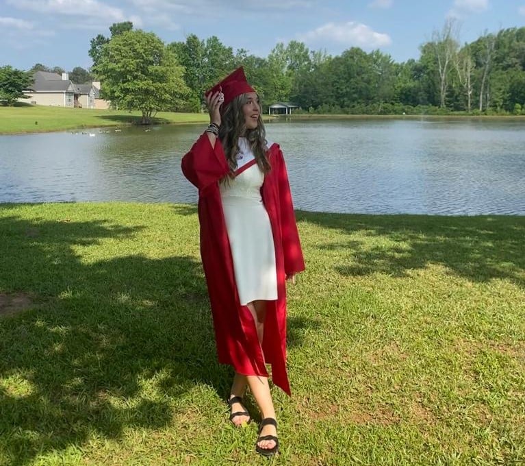 girl in cap & gown in front of lake