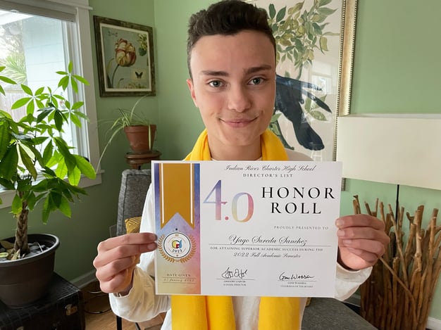 boy holding 4.0 honor roll certificate