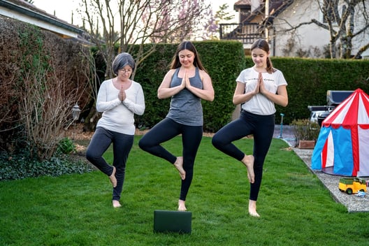 mom and two daughters doing yoga in yard