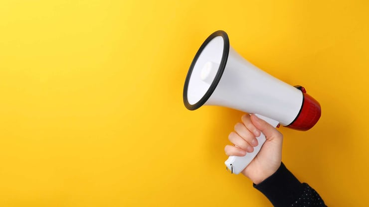 a hand holding a megaphone against a yellow background