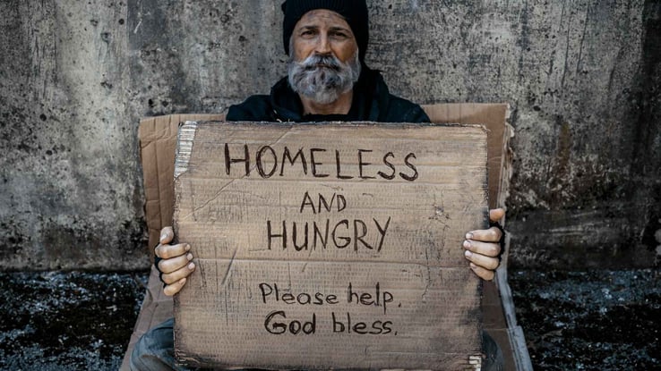 a homeless man holding a sign asking for help