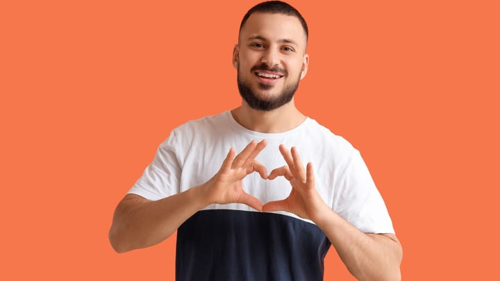 a young man making heart hand signal over his heart