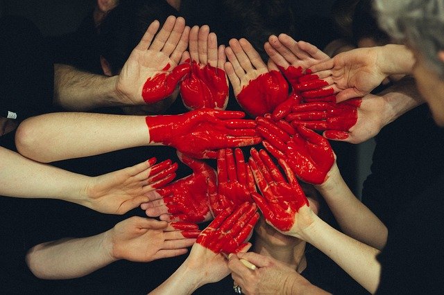 Many hands together with a big red heart painted on them