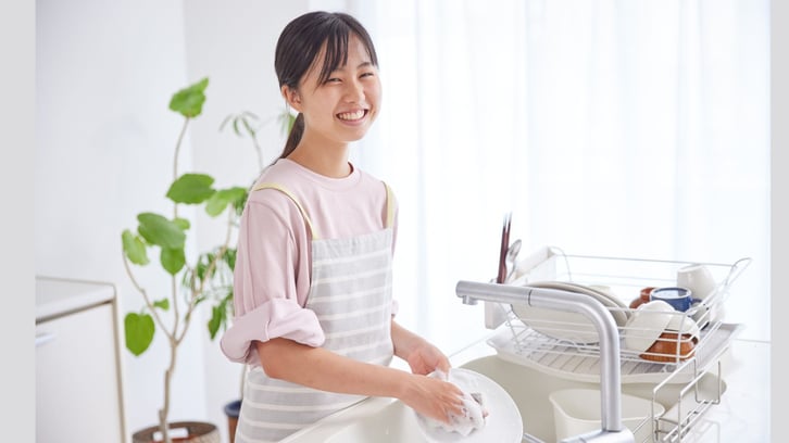 asian girl washing dishes and smiling