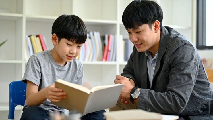 asian teenage boy helping younger boy with homework