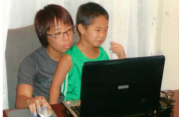 big brother with little brother on lap in front of computer