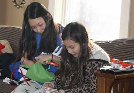 big sister and little sister opening Christmas gifts together