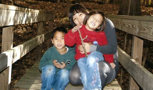 big sister with little brother and sister together on a bridge