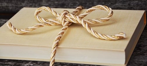 a beige book with a beige and gold cord tied in a bow