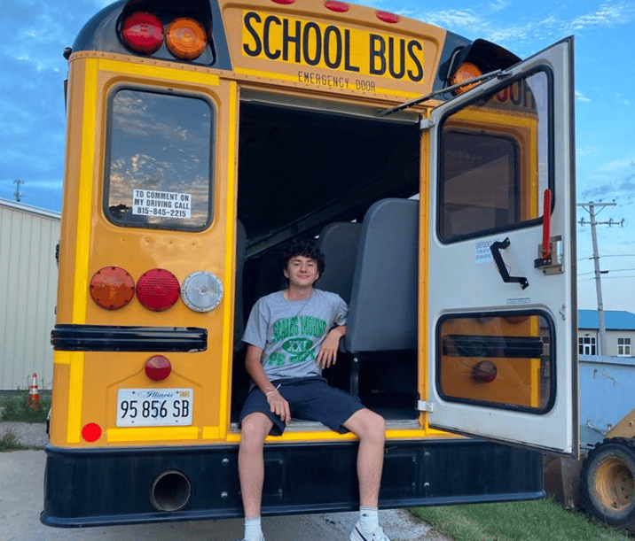 teen boy sitting in back of school bus