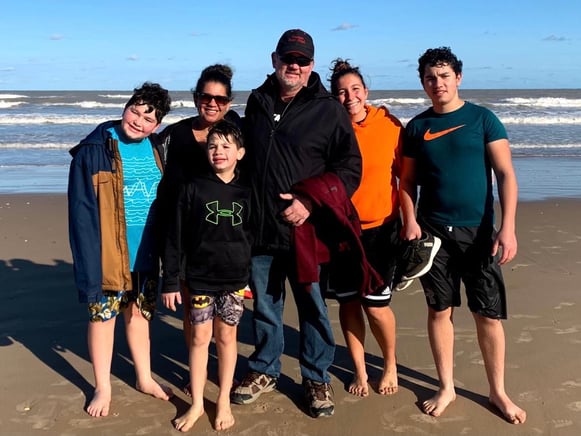 Vanessa and host family on the beach with ocean behind