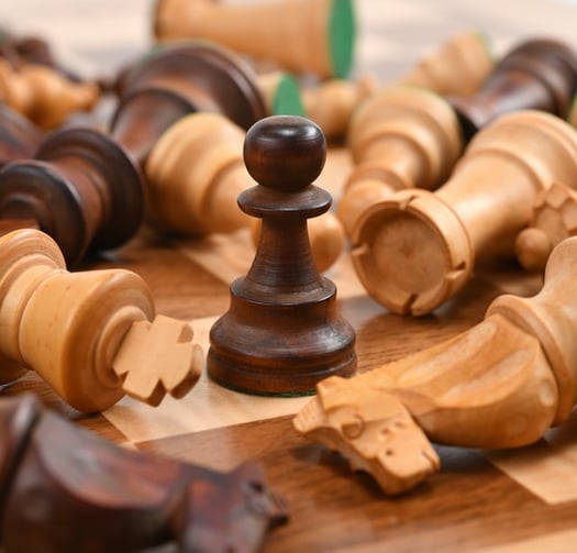 chess pieces knocked over with one standing