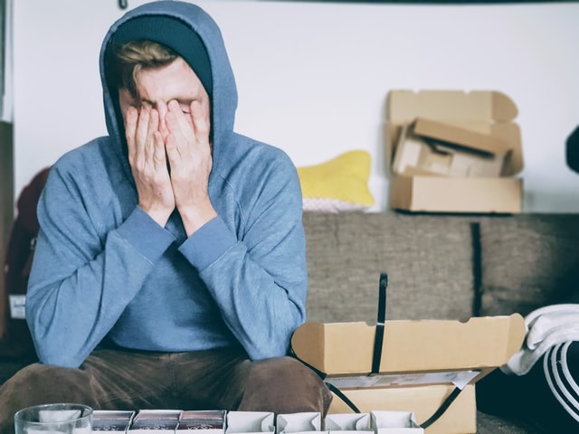 a teenage boy covering his face with his hands