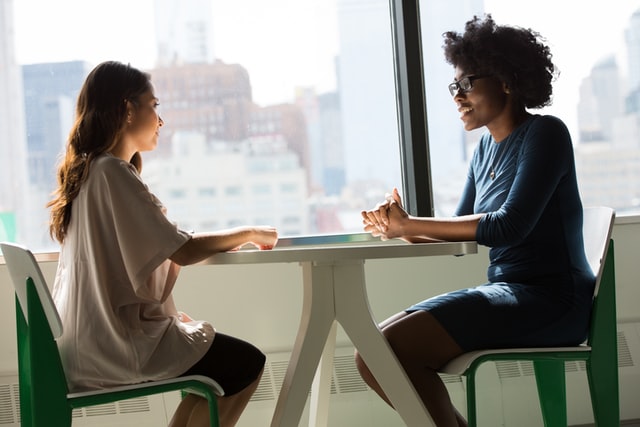 a teenager sitting with a young woman talking at a table