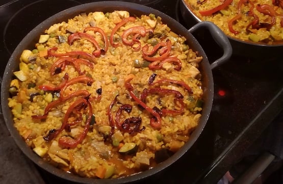 A creative paella with a mix of vegetables and meat topped with red peppers