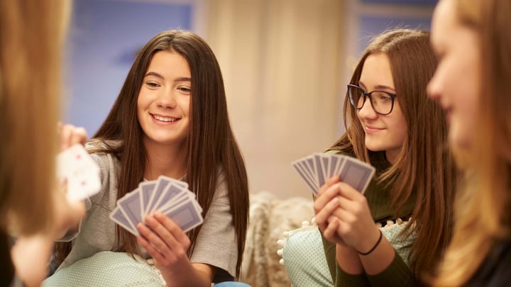 family game night with two twin teen girls holding cards and smiling