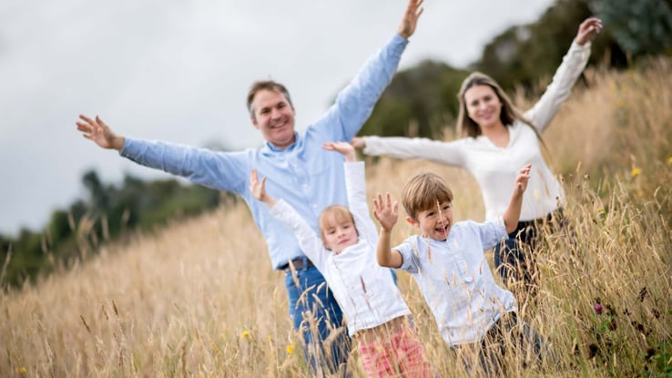 family in a field with open arms