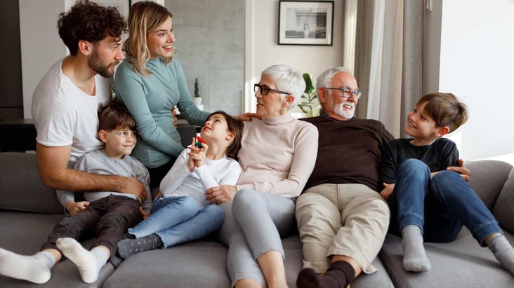 family sitting on sofa together with parents grandparents and children