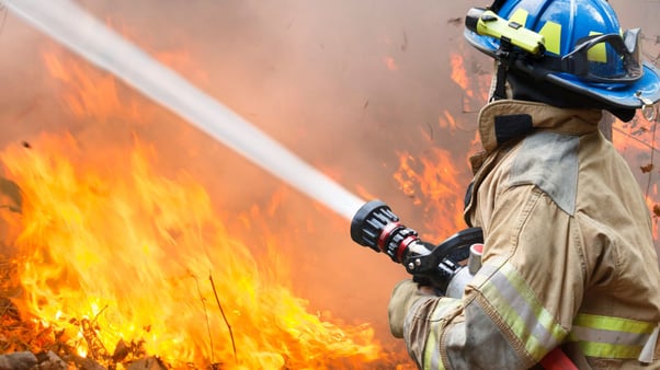 firefighter spraying water on a blazing fire