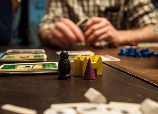 game player holding cards with wooden tokens on the board