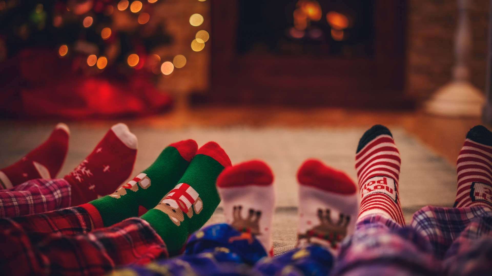 four sets of feet wearing christmas socks