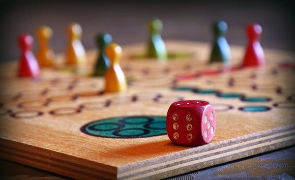 colored tokens and a red die on a wooden game board