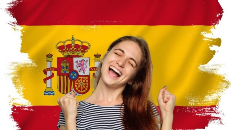 girl raises fists triumphantly and happily with Spanish flag behind