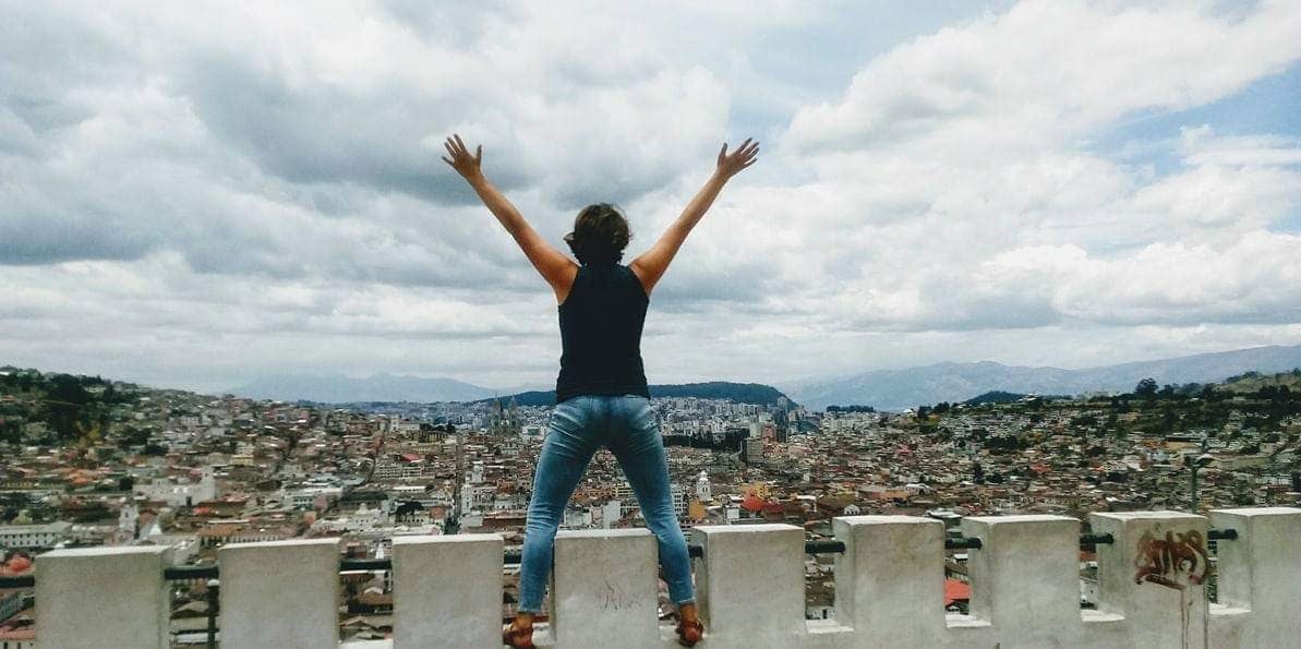 girl with raised arms facing city