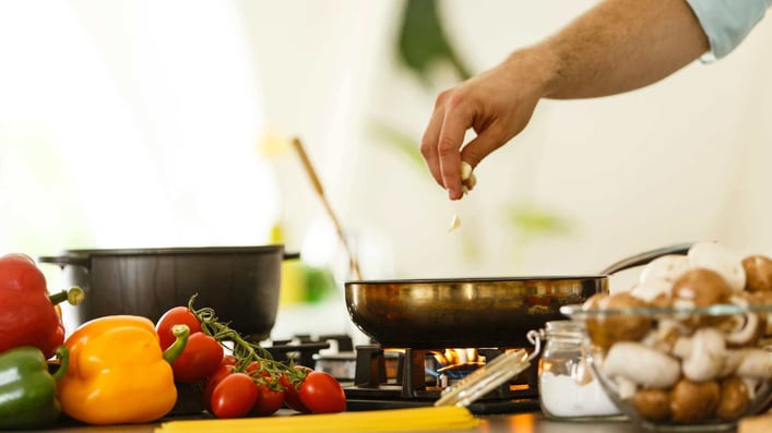 hand of a man adding ingredient to fry pan