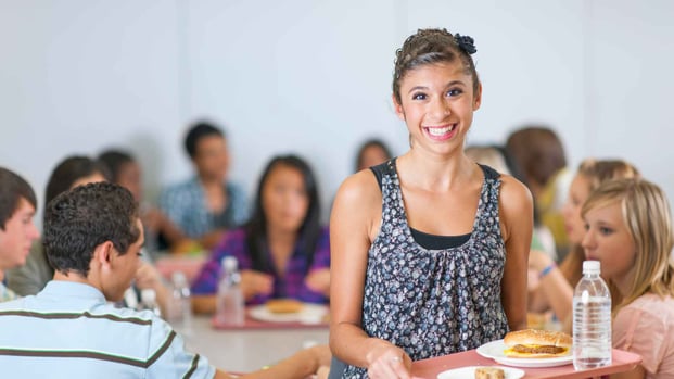 high school student holding tray in cafeteria