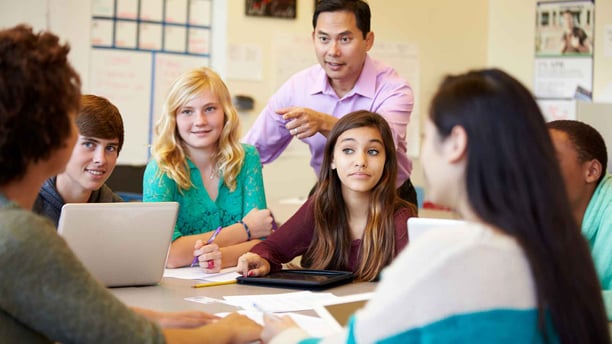 high school teacher smiling and helping students