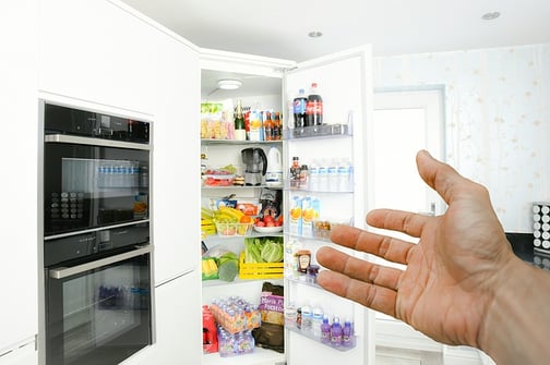 a man's hand gestures towards an open refrigerator