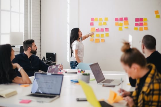 student at front of class arranging sticky notes on white board