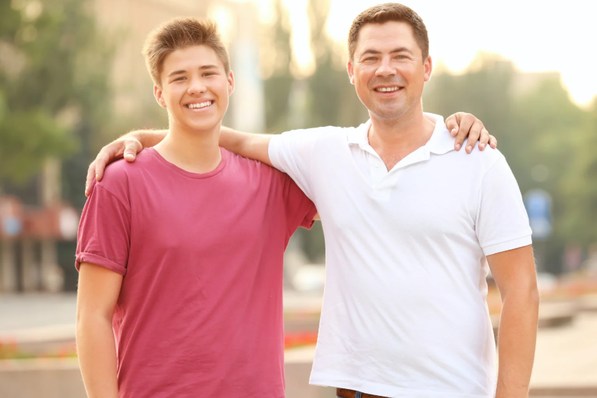 man and teen with arms around shoulders