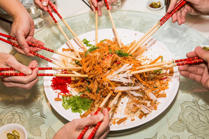 7 people sharing a dish with chop sticks