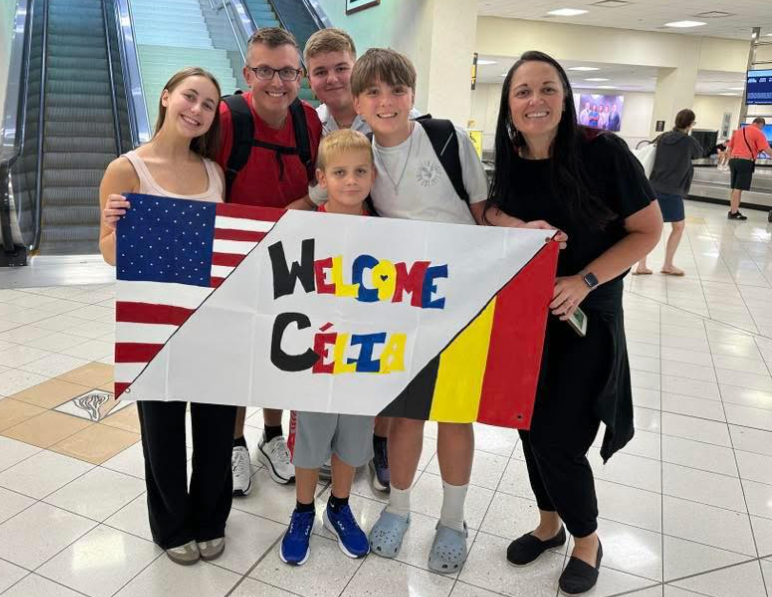 family with colorful welcome sign at airport with student
