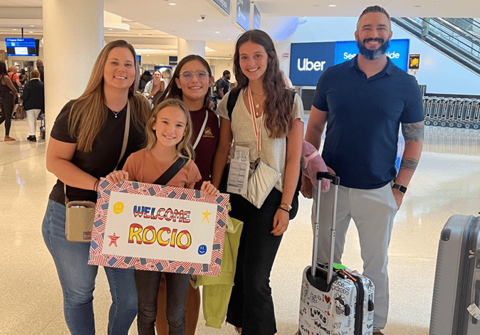 family greeting an exchange student at airport