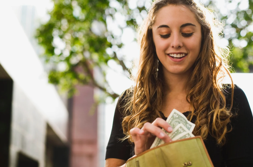 teen pulling dollars from wallet
