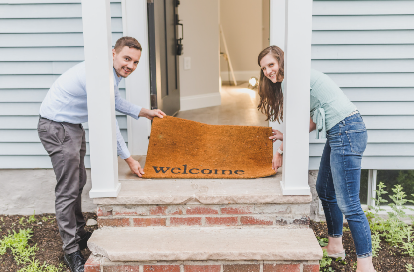 young couple putting out welcome mat