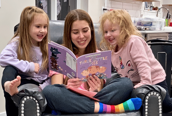 teen girl reading to 2 young girls