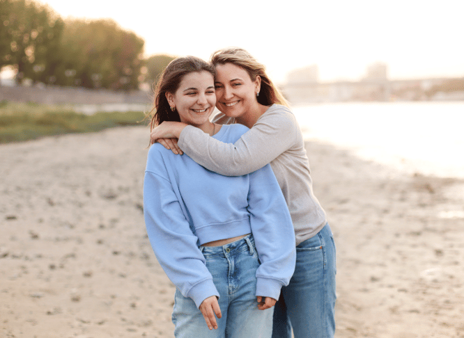 host mom hugging exchange student on beach