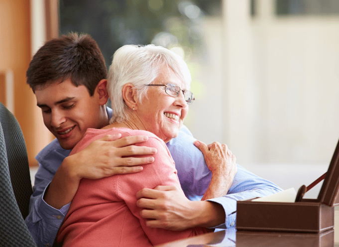 teen boy hugging senior woman